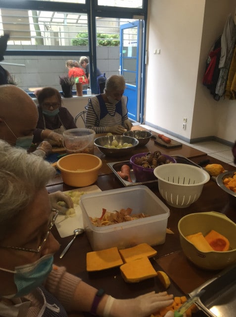 Seniorzy podczas pracy przy stole podczas warsztatów kulinarnych