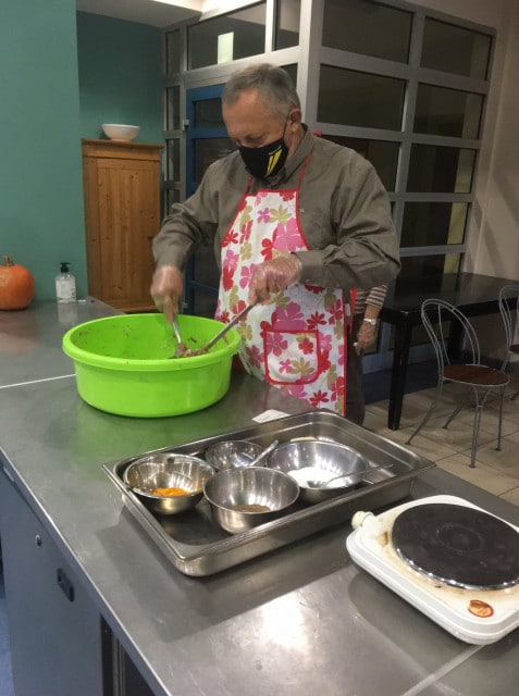Jeden z seniorów podczas przyrządzania potrawy w zielonej misce