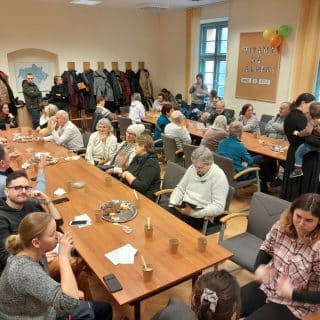 Grupa ludzi siedzi przy stołach w sali