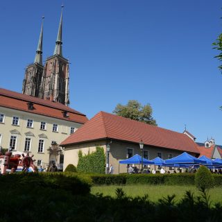 Plac festynowy z dmuchańcem i niebieskimi namiotami, w tle górują wieże katedry