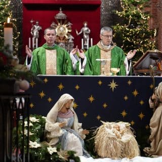 Dwóch kapłanów przy ołtarzu z małą szopką