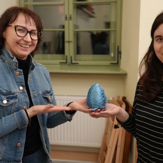 Dwie kobiety wskazują na jajko wielkanocne zrobione z niebieskiej wstążki