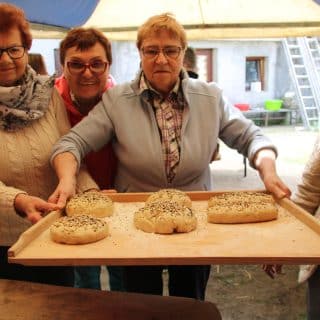 Cztery seniorki ze stolnicą, na której kilka chlebków gotowych do wypieku