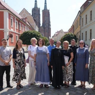 Zdjęcie grupowe kilkunastu osób na tle wrocławskiej katedry