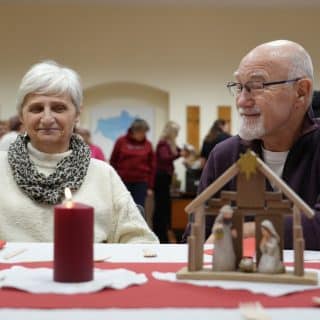 Kobieta i mężczyzna przy stole, na którym stoi świeca i żłóbek