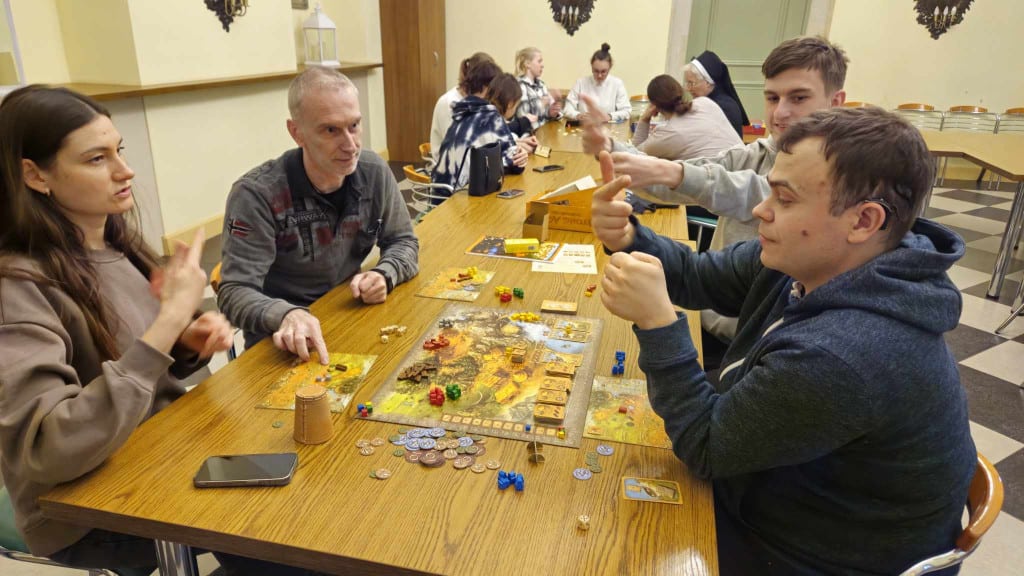Przy długim stole w dwóch grupach grają w gry planszowe