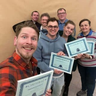 Kilka osób w sali pozuje do zdjęcia z certyfikatami