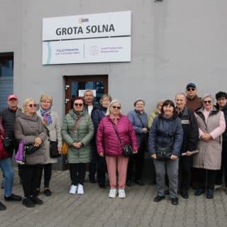 Grupa seniorów przed budynkiem z napisem grota solna