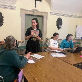 W sali dwie osoby migają ze sobą obok dwóch osób przy komputerze