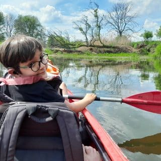 Chłopiec z wiosłem płynie kajakiem