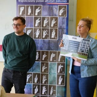 Mężczyzna i kobieta przy planszy z alfabetem języka migowego