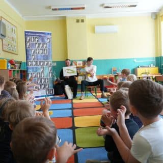 Migające przedszkolaki w sali naśladują nauczyciela