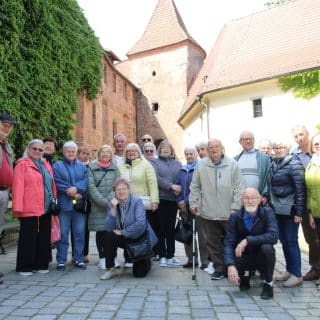 Grupa seniorów na tle budynków arsenału miejskiego