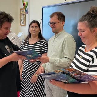 W sali szkolnej trzyosobowa komisja wręcza dyplom kobiecie