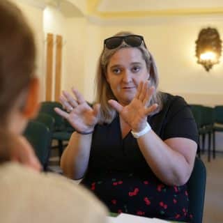 Migająca kobieta w sali konferencyjnej siedzi przy stoliku