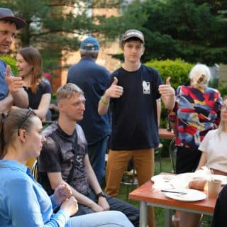 Grupa osób podczas rozmowy przy stole w ogrodzie