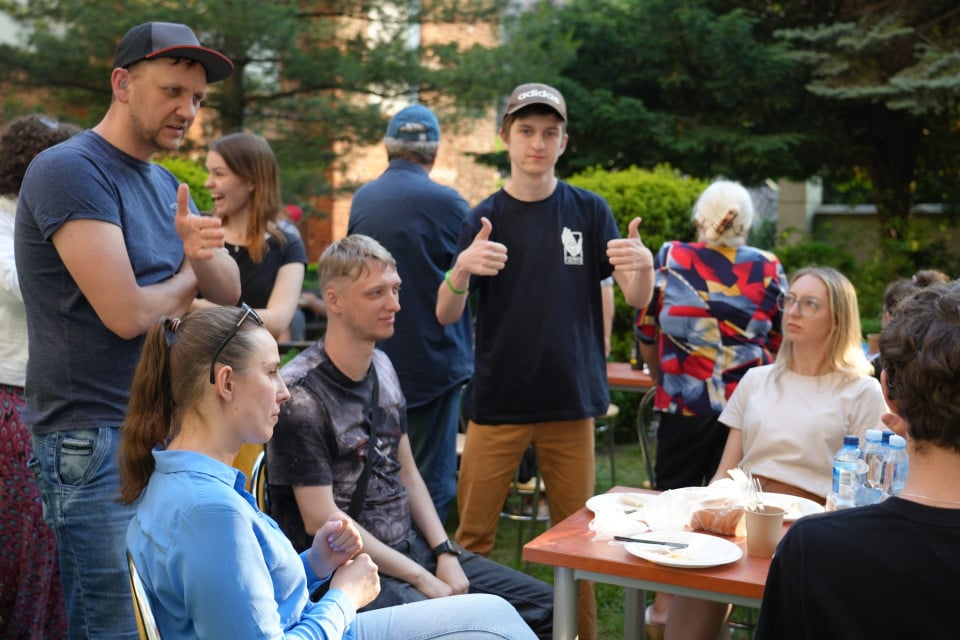 Grupa osób podczas rozmowy przy stole w ogrodzie
