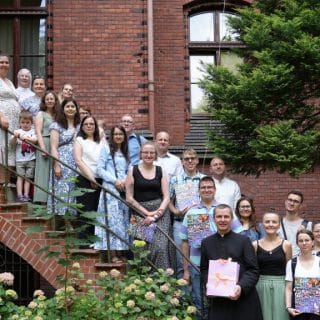 Grupa ludzi stojąc na schodach pozuje do zdjęcia