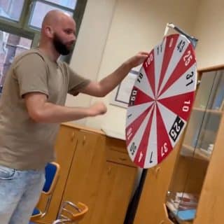 Mężczyzna kręci dużym biało-czerwonym kołem z różnymi liczbami