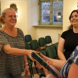 Uśmiechnięta kobieta podaje dłoń kobiecie wręczającej jej dyplom