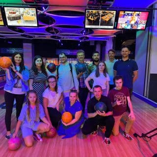 Kilkanaście osób pozuje do zdjęcia w kręgielni