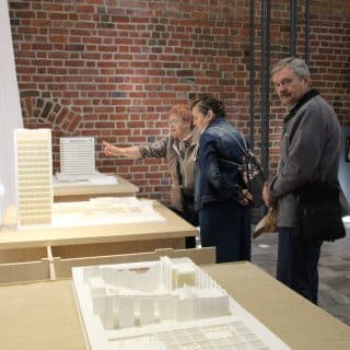 Kilka osób ogląda modele budynków w sali