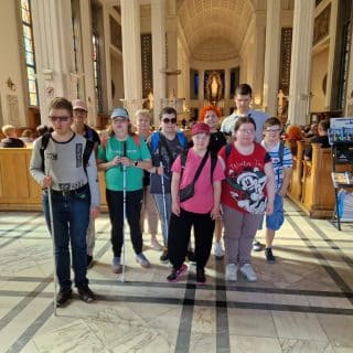 Grupa młodzieży z białymi laskami pośród ludzi w kościele