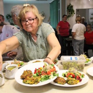 Kobieta ustawia talerze z daniem obiadowym na szerokiej ladzie