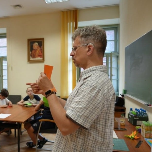 Mężczyzna z aparatem słuchowym w sali trzyma w dłoniach kartkę papieru