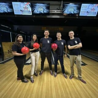 Pięć osób pozuje do zdjęcia w sali do gry w kręgle