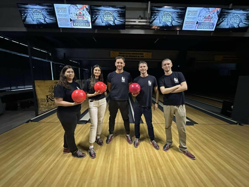 Pięć osób pozuje do zdjęcia w sali do gry w kręgle