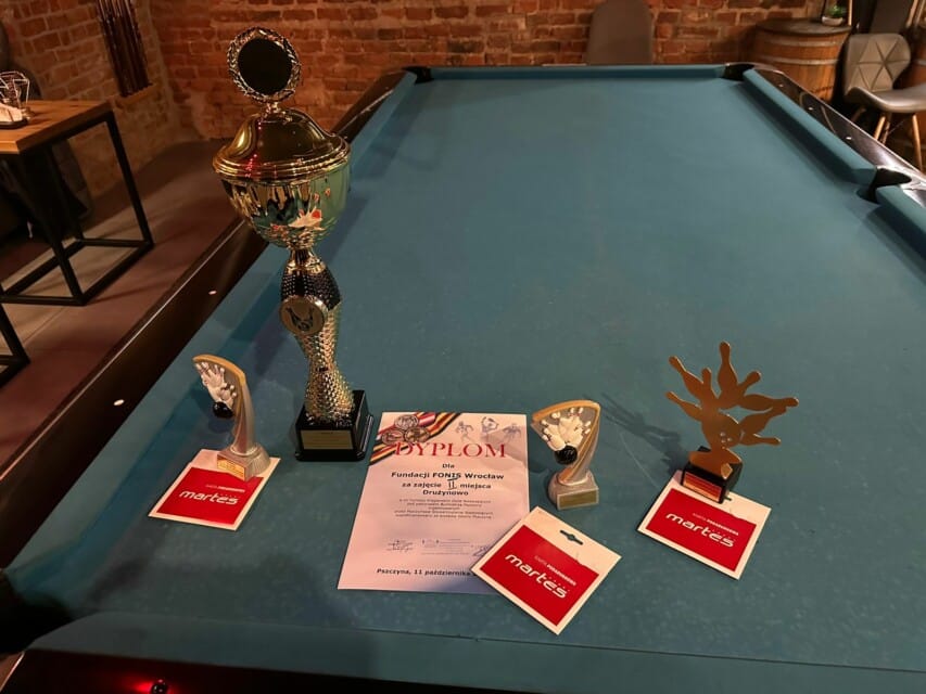Puchary i dyplom leżące na stole bilardowym