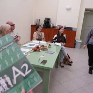 Podręcznik do kursu PJM A2 na tle grupy osób w sali