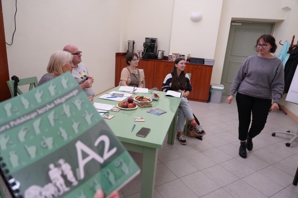 Podręcznik do kursu PJM A2 na tle grupy osób w sali