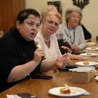 Kobieta mówiąca do mikrofonu siedzi przy stole