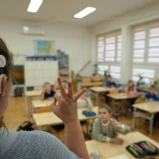 Dzieci w sali lekcyjnej naśladują migającą kobietę z implantem