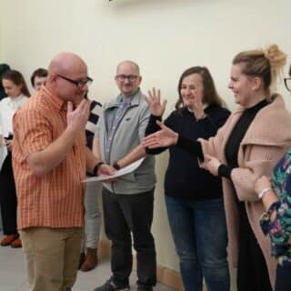 Mężczyzna w gronie kilku osób odbiera dyplom