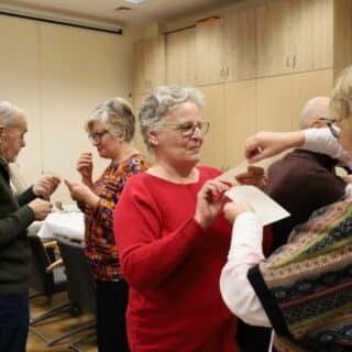 Kilka osób w sali podczas łamania się opłatkiem