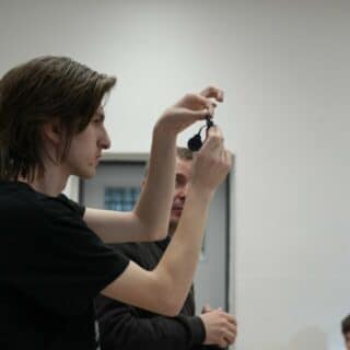 Młody mężczyzna w sali lekcyjnej pokazuje implant ślimakowy