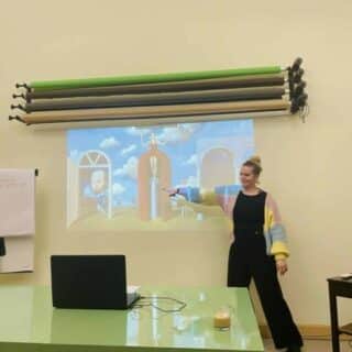 Kobieta pokazuje dłonią na obraz wyświetlony z rzutnika