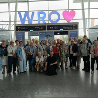 Zdjęcie grupowe na tle wyjścia z lotniska z napisem WRO